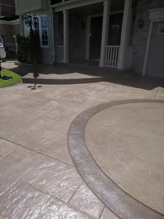 Brown stamped concrete driveway with a curved inset border