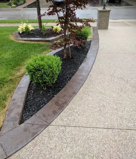 A curving aggregate walkway next to a landscaped lawn