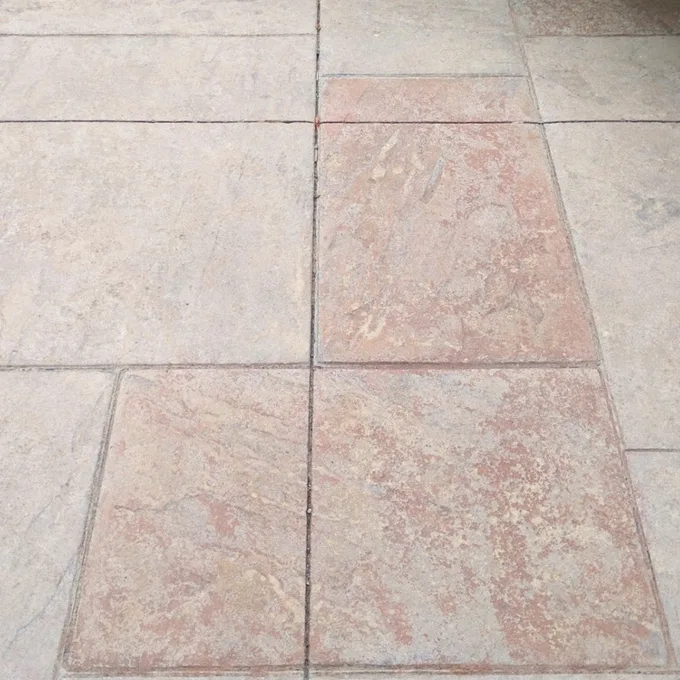 Grey and terracotta stamped concrete before sealing, with dull, weathered rectangular panels